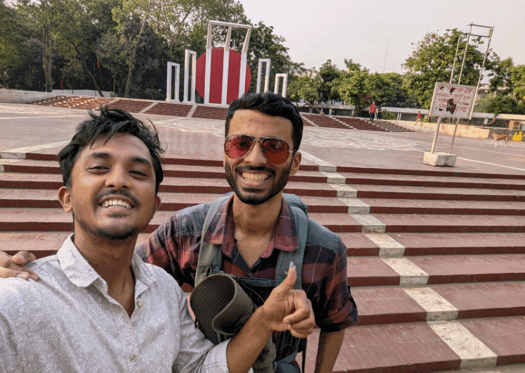 Two travelers taking a selfie in front of the Shaheed Minar monument in Dhaka, Bangladesh, during a TripGlider cultural and food tour.