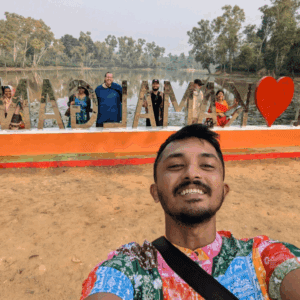 A traveler taking a selfie in front of the decorative "I Love Madhabpur" landmark at Madhabpur Lake in Sreemangal, Bangladesh.